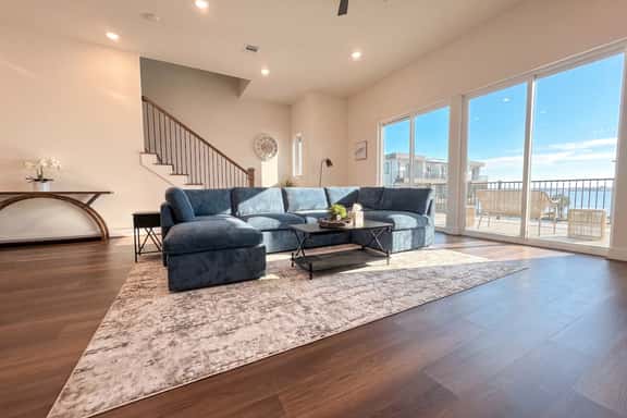 Bright open living room with large sectional and balcony water views